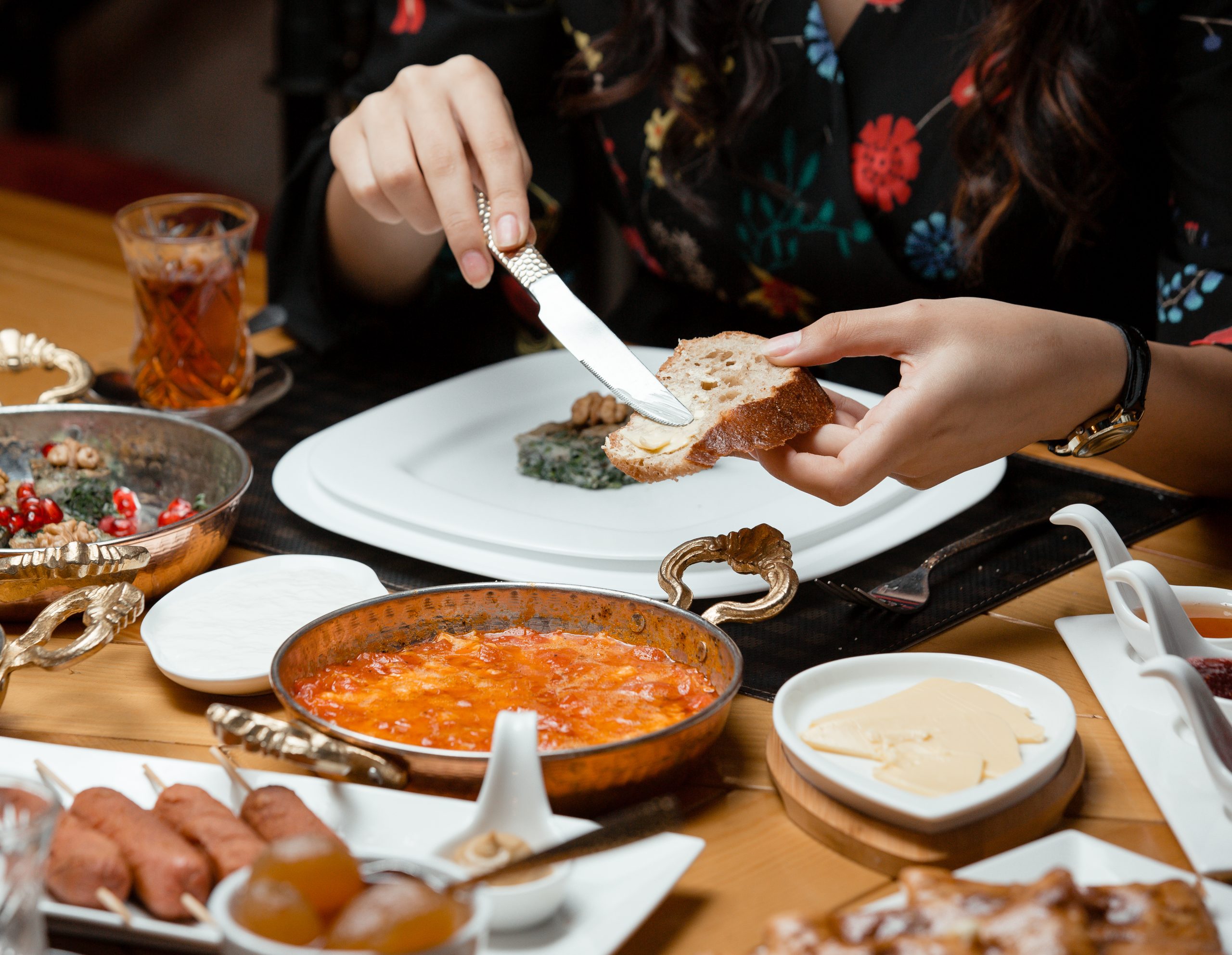 woman spreading butter on bread in traditional breakfast setup