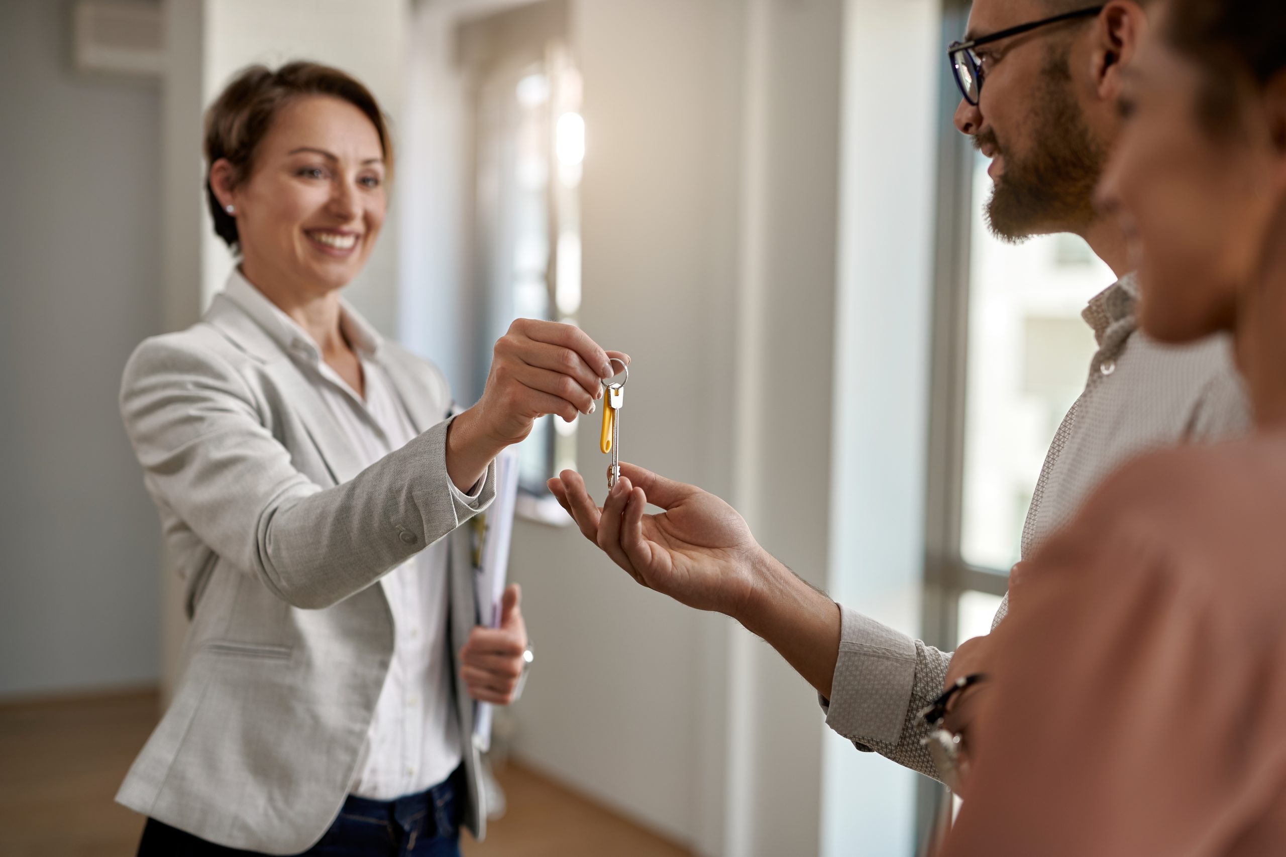 Happy real estate agent giving to a couple keys of their new home.
